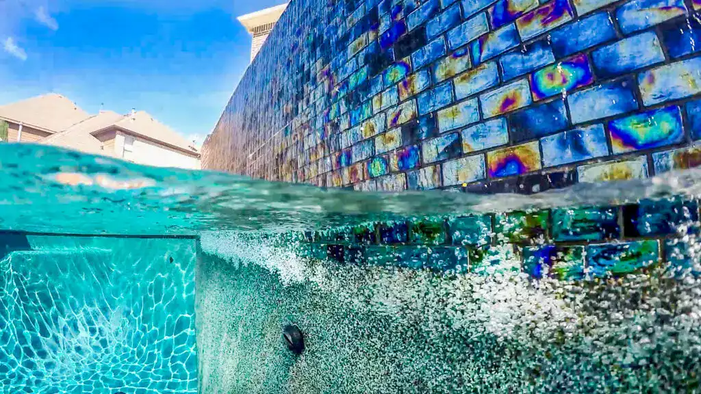 Vivid blue pool with decorative tiled wall for luxurious backyard oasis. Perfect for remodeling or new pool finishes.