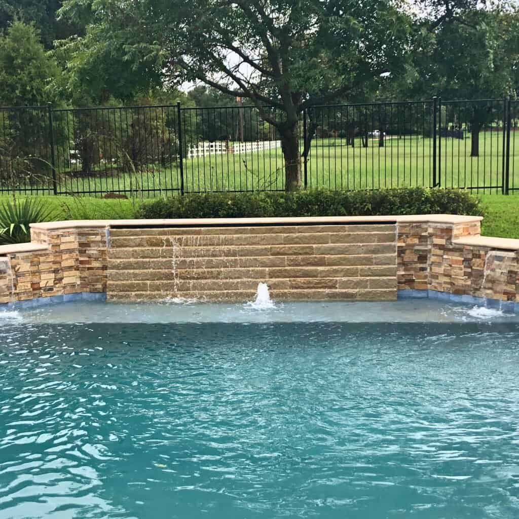 Aluminum pool with stone waterfall feature and fresh plaster finish.