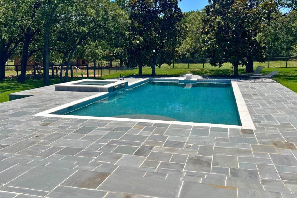 Bright blue pool with stylish stone deck, perfect for outdoor relaxation and entertainment.