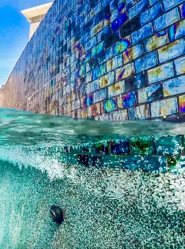 Vivid blue pool with decorative tiled wall for luxurious backyard oasis. Perfect for remodeling or new pool finishes.