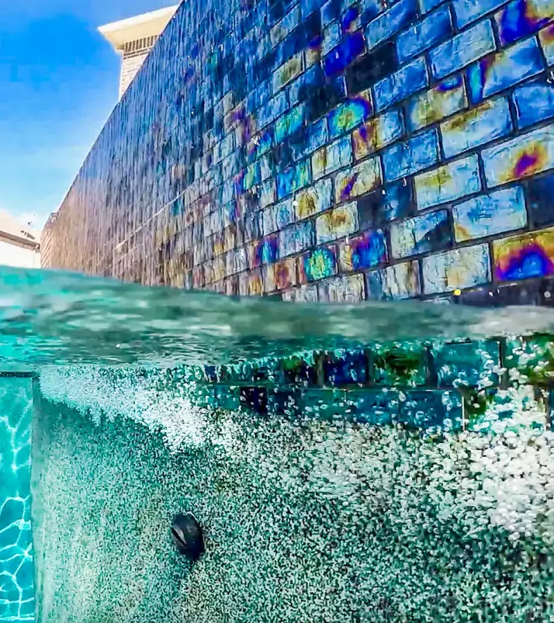 Vivid blue pool with decorative tiled wall for luxurious backyard oasis. Perfect for remodeling or new pool finishes.