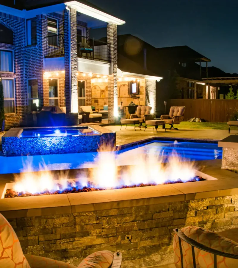 Beautiful backyard pool with fire pit, lighting, and outdoor seating for relaxing evenings.