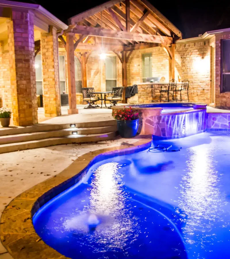 High-quality custom pool plastering with illuminated night lighting and luxurious backyard design.